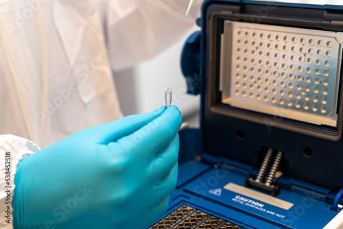 Loading a DNA tube into a PCR (polymerase chain reaction) thermocycler machine in a bioscience laboratory. PCR Thermal Cyclers. Coronavirus (COVID-19) treatment. photo