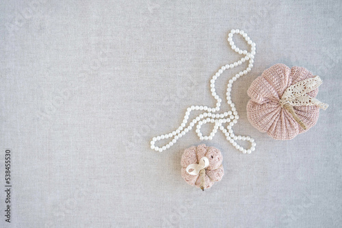 Hobby background with handmade knit pumpkins and white pearl beads. DIY, craft decoration for fall and winter holidays. Flat lay, top view