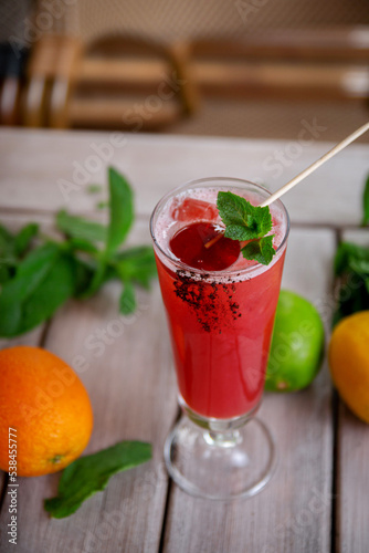 alcoholic cocktail with candy and mint leaves of sake, raspberry, passion fruit, violet liqueur and pineapple juice