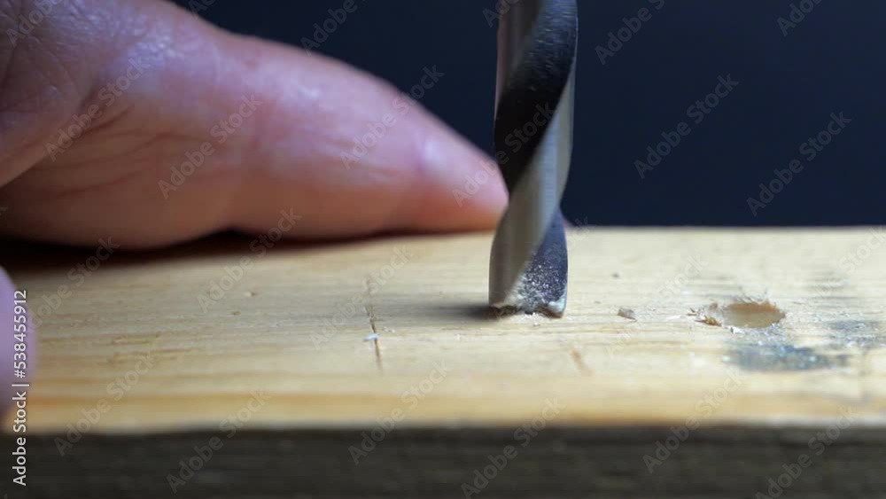 Slow motion close up of drill bit drilling into wood. Joinery and construction work close up. Wood chippings fly off a metal drill. Handyman bores holes into a wooden board. Slow motion close up of drill bit drilling into wood. Joinery and construction work close up. Wood chippings fly off a metal drill. Handyman bores holes into a wooden board.