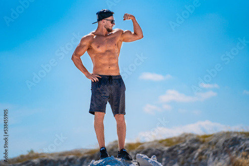 Fitness sporty person with athlete torso. Strong shirtless man outdoor landscapes.