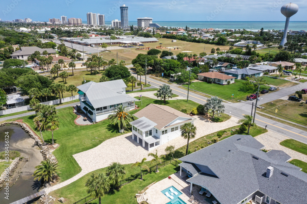 Aerial looking north over Daytona Beach Shores residential riverfront neighborhood in the foreground with Daytona Beach high rise condos and hotels in the background.