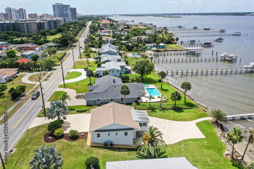 Aerial looking south over Daytona Beach Shores residential riverfront neighborhood in the foreground with high rise condos and hotels in the background.