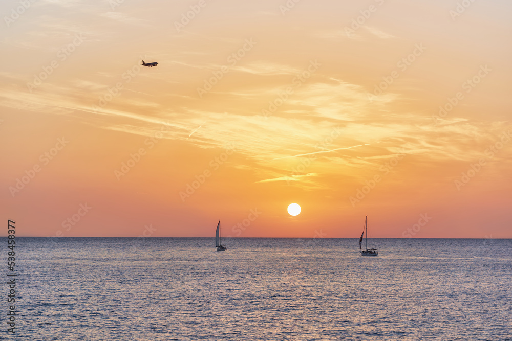 View of the yachts in the sea and the plane in the light of the setting sun. Rest on the sea.