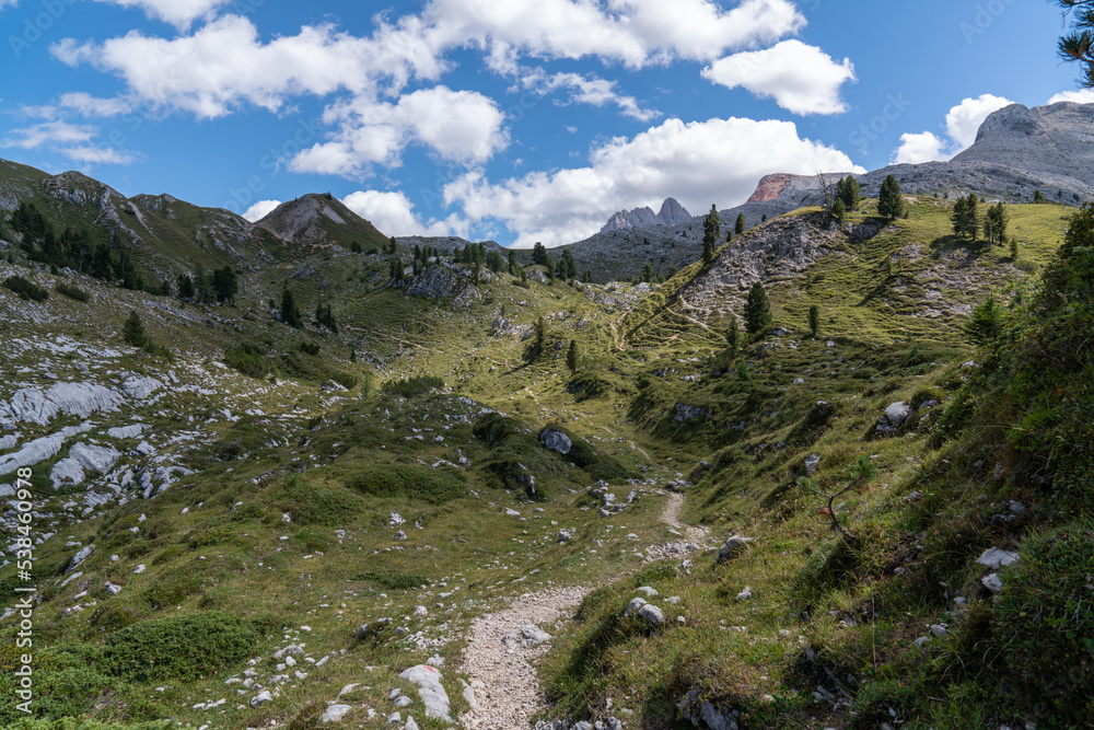 Obraz premium High rocks. Alps in Italy. South Tyrol. Dolomites. Green landscape with stones and trees. Paths in the mountains. Travel. Tourist places. Beautiful nature. Blue clouds