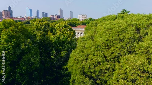 Aerial view of summer trees in Giardini Indro Montanelli park and skyline with new skyscrapers. View of modern business offices. Business. Tourism. Ecology. Clouds over the city. Green Planet. Milan.  photo
