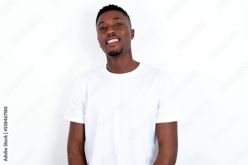 young handsome man wearing white T-shirt over white background with broad smile, shows white teeth, feeling confident rejoices having day off. young handsome man wearing white T-shirt over white background with broad smile, shows white teeth, feeling confident rejoices having day off.