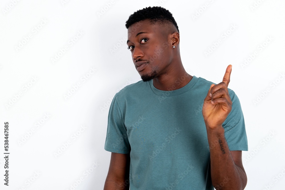 No sign gesture. Closeup portrait unhappy young handsome man wearing green T-shirt over white background raising fore finger up saying no. Negative emotions facial expressions, feelings. No sign gesture. Closeup portrait unhappy young handsome man wearing green T-shirt over white background raising fore finger up saying no. Negative emotions facial expressions, feelings.