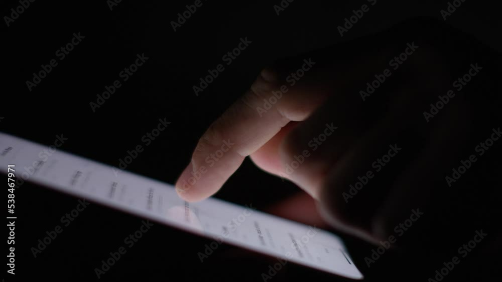 Profile shot of finger scrolling over a cell phone screen in the dark
