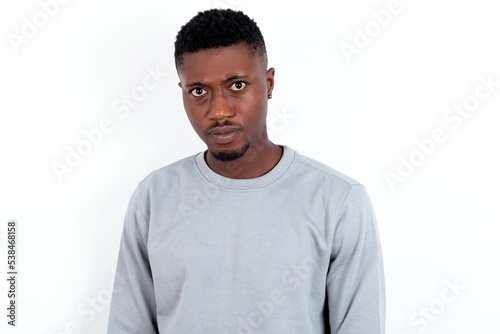 young handsome man wearing grey sweater over white background Pointing down with fingers showing advertisement, surprised face and open mouth