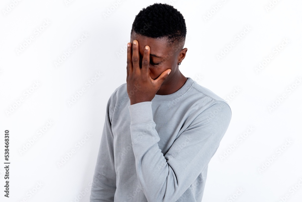 young handsome man wearing grey sweater over white background with sad expression covering face with hands while crying. Depression concept. young handsome man wearing grey sweater over white background with sad expression covering face with hands while crying. Depression concept.