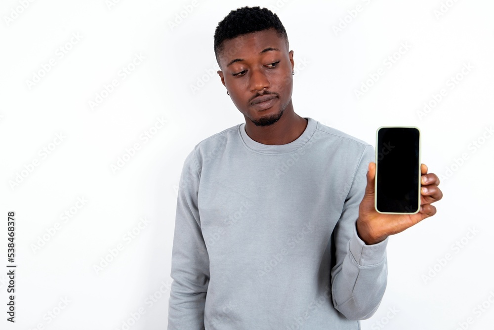 Photo of interested young handsome man wearing grey sweater over white background hold telephone look side empty space screen Photo of interested young handsome man wearing grey sweater over white background hold telephone look side empty space screen
