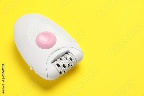 Modern epilator on yellow background, closeup. Space for text