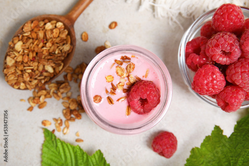 Tasty raspberry smoothie with granola in glass jar and fresh berries on light table, flat lay