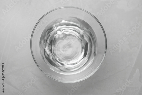 Glass bowl with water on grey table  top view