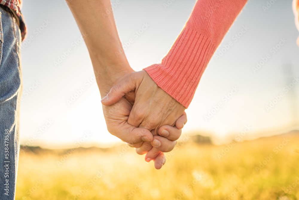 couple closeup holding hands together sunset couple closeup holding hands together sunset