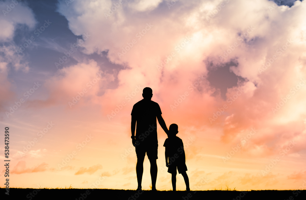 Parent and child young father and son standing together looking at the sunset.. Parenting, and family relationship concept. 
