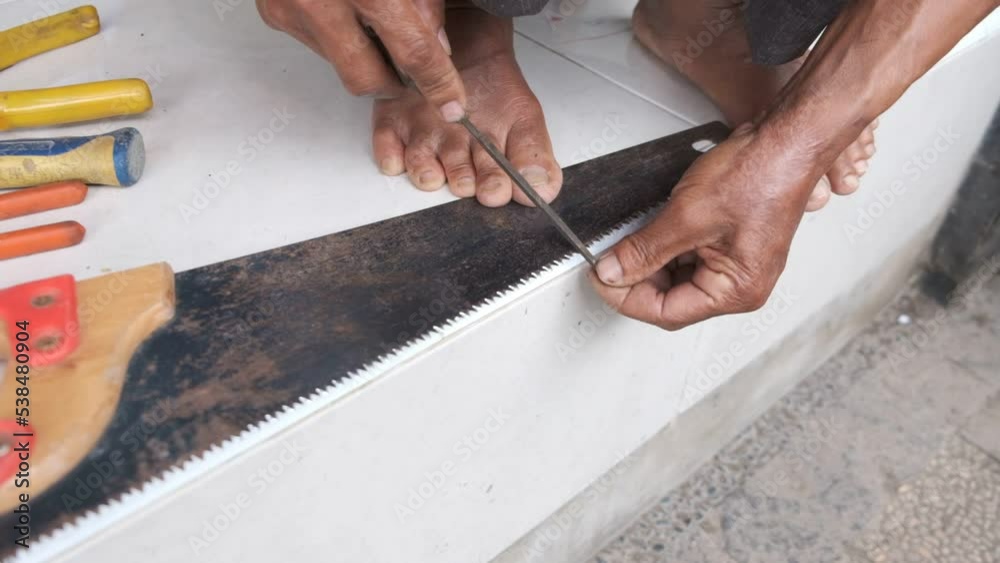 A Worker man Doing Sharpening Tool of His Old Rusty Saw Tooth in Manual Process A Worker man Doing Sharpening Tool of His Old Rusty Saw Tooth in Manual Process