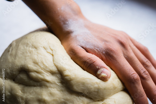 Hand of an unrecognizable person on dough to prepare bread.