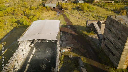 Aerial view of a abandoned factory next to mountain range covered with autumn golden trees and higher mountains