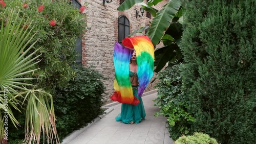 belly dancer performing with colorful assesories among ancient buildings and tropical plants in slow motion photo