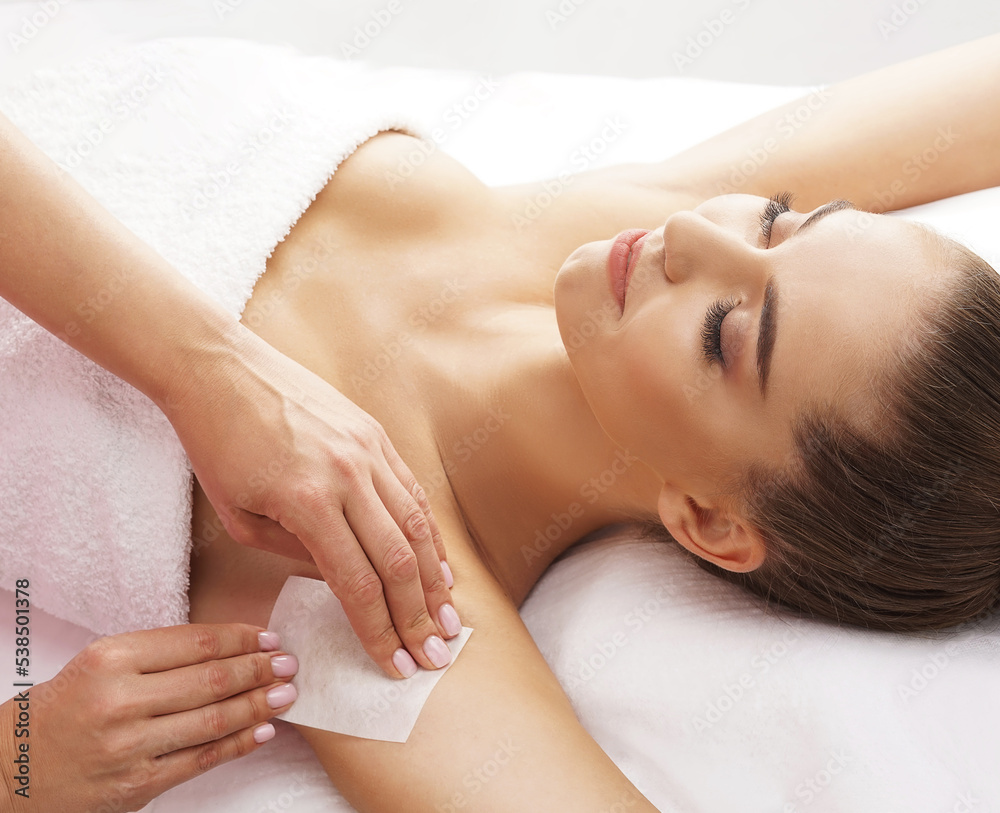 Hair removal, beauty and health concept. A young girl is getting an epilation procedure. A processional beauty worker is making depilation with hot wax. Hair removal, beauty and health concept. A young girl is getting an epilation procedure. A processional beauty worker is making depilation with hot wax.