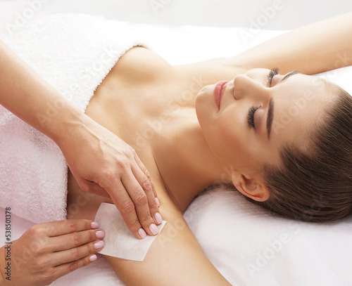 Hair removal, beauty and health concept. A young girl is getting an epilation procedure. A processional beauty worker is making depilation with hot wax.