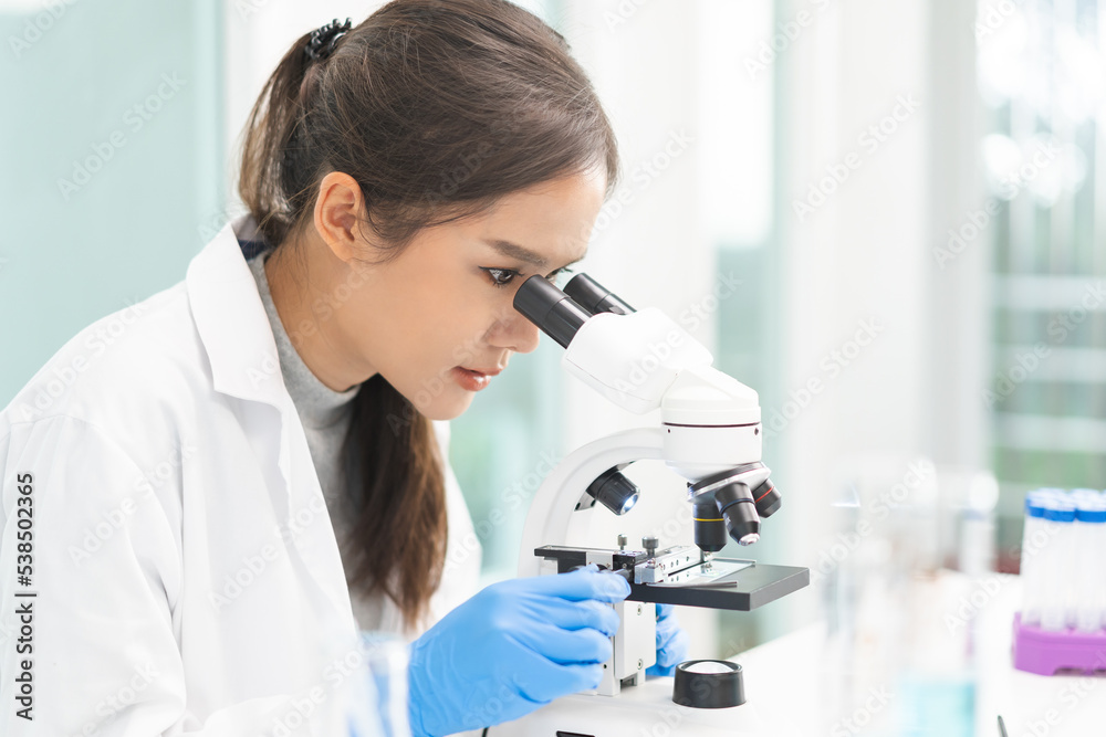 Medical development research laboratory, science young woman scientist in glasses, glove looking under microscope for test analysis samples in lab. Microbiology, analysing biochemicals for medicine Medical development research laboratory, science young woman scientist in glasses, glove looking under microscope for test analysis samples in lab. Microbiology, analysing biochemicals for medicine