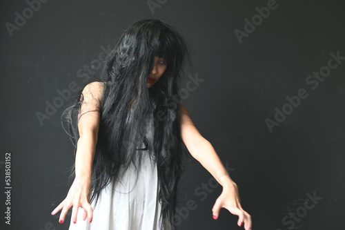 Happy Halloween day in Scary ghost woman. Asian ghost or zombie horror creepy scary have hair covering face and eye reach arm out at abandoned house dark room. 