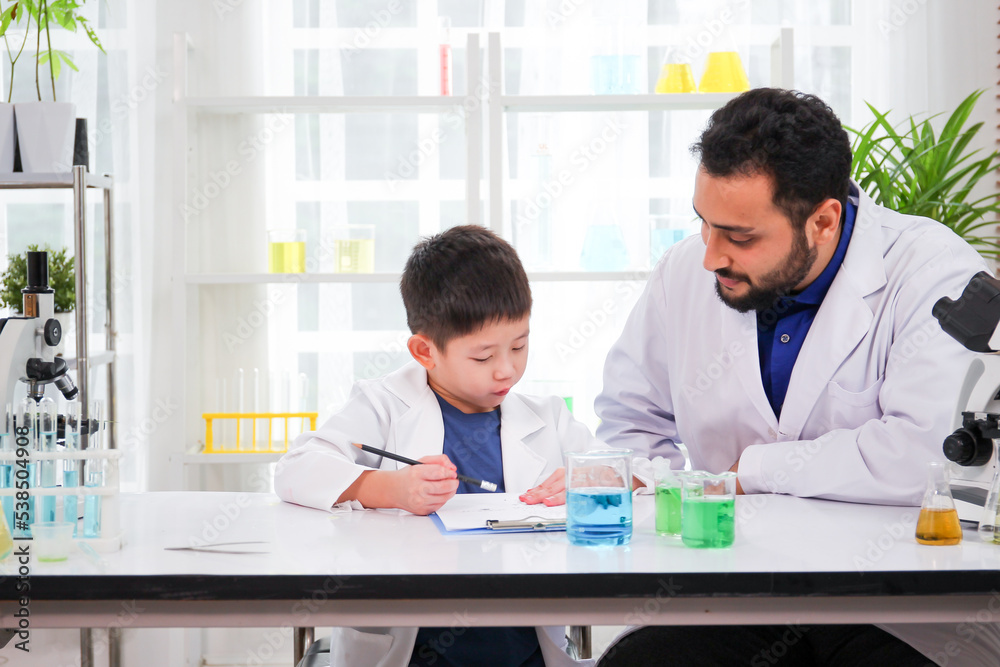 Lovely Asian young boy in lab coat enjoy doing an experiment and studying a science. 