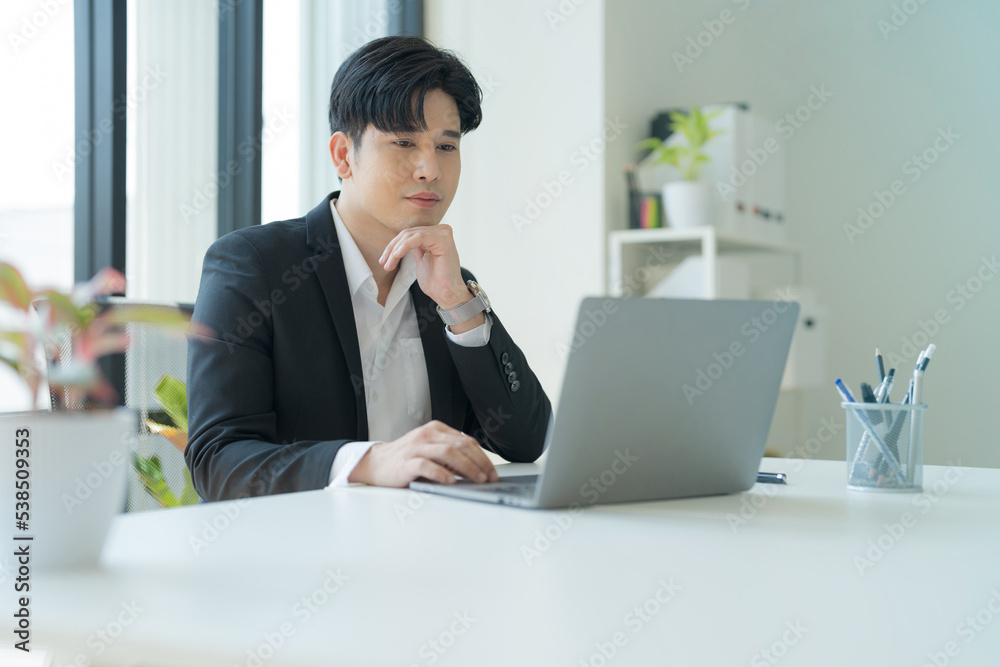 Attractive businessman working on laptop in workstation office. Attractive businessman working on laptop in workstation office.