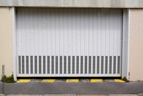 Automatic white gate door with electric rocker at the entrance of the apartment building residence for the car garage
