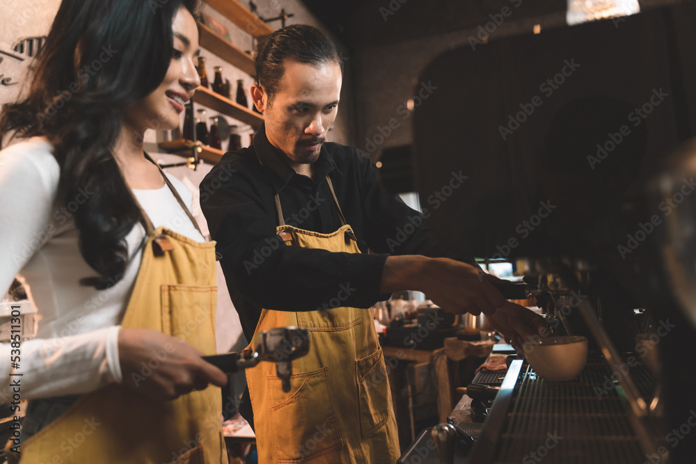 happiness two waiter teaching woman with apron to use a coffee machine for make a coffee. the happiness men and woman in bakery small business on waiter and waitress uniform.