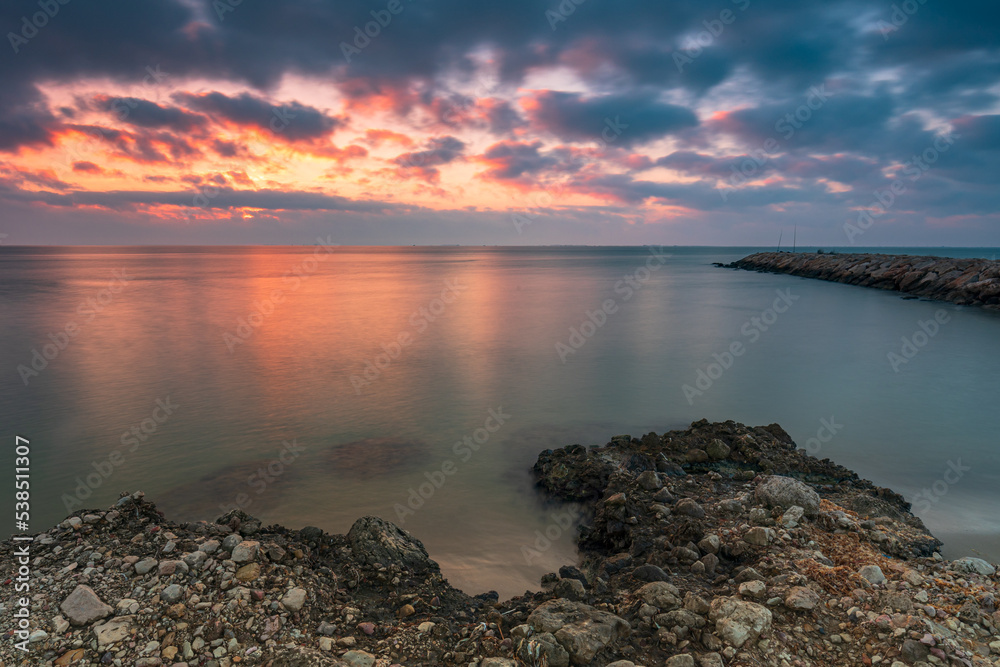 Sunrise on a rocky beach with amazing colors. Ebro Delta. God concept, end concept.