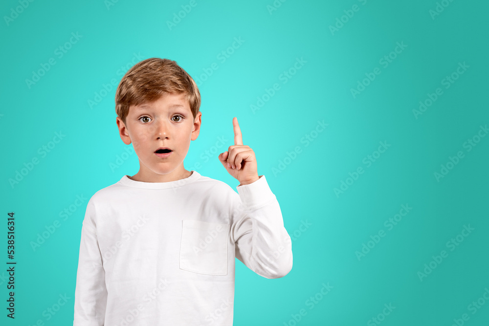 Boy with finger pointing up, surprised portrait and bright empty background Boy with finger pointing up, surprised portrait and bright empty background