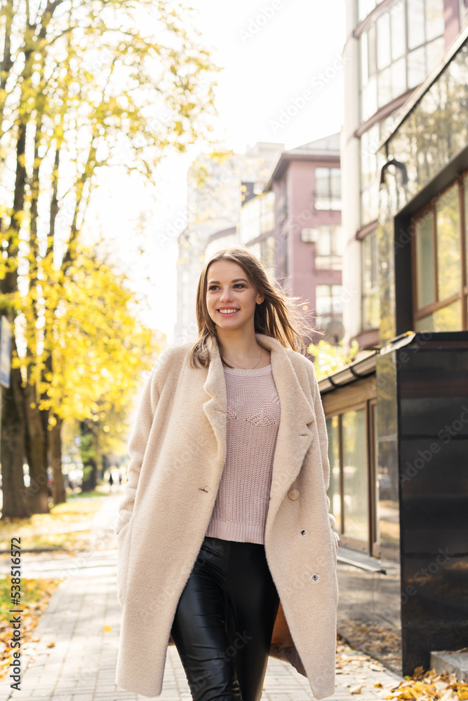 Fototapeta premium Happy Woman wearing coat walking in the sunny city