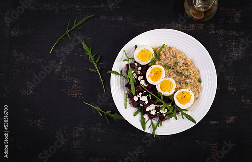 Breakfast oatmeal porridge with boiled eggs, beetroot and green herbs. Healthy balanced food. Top view