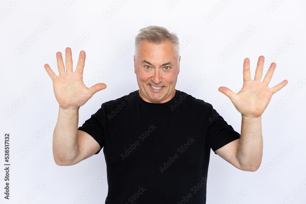 Naklejka premium Portrait of excited senior man showing ten fingers. Happy Caucasian male model in black T-shirt with gray hair looking at camera, smiling while counting. Countdown concept.