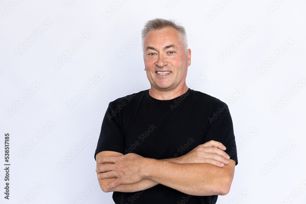 Portrait of confident senior man crossing arms. Proud Caucasian male model in black T-shirt with gray hair smiling, looking at camera with crossed arms. Studio shot, self-assurance concept. Portrait of confident senior man crossing arms. Proud Caucasian male model in black T-shirt with gray hair smiling, looking at camera with crossed arms. Studio shot, self-assurance concept.