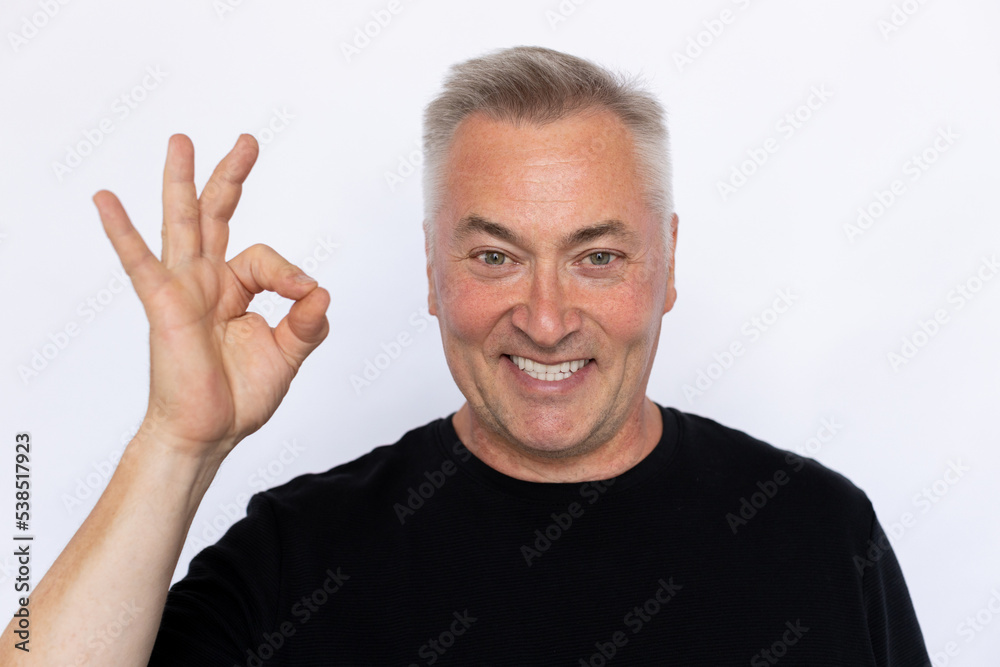 Closeup of happy elderly man making ok sign. Excited Caucasian male model in black T-shirt with gray hair looking at camera, smiling while showing ok gesture. Approval concept. Closeup of happy elderly man making ok sign. Excited Caucasian male model in black T-shirt with gray hair looking at camera, smiling while showing ok gesture. Approval concept.
