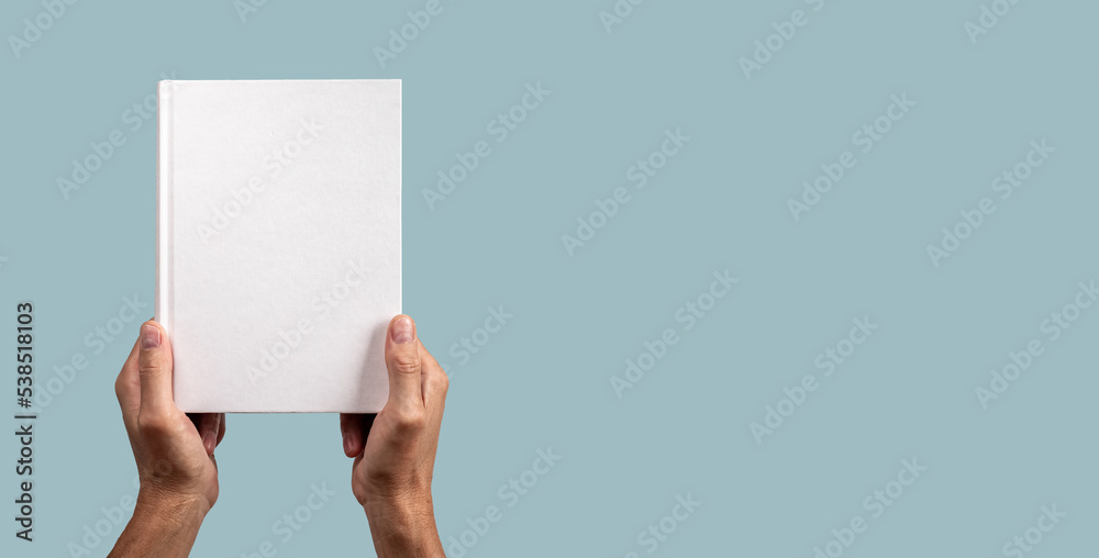 Paper business book mock up in male hand on blue banner with copy space. Hard cover mockup, blank template - obrazy, fototapety, plakaty 