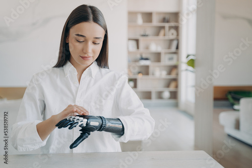 Girl adjust settings of bionic prosthetic arm, touch sensory panel on upper side of artificial hand photo