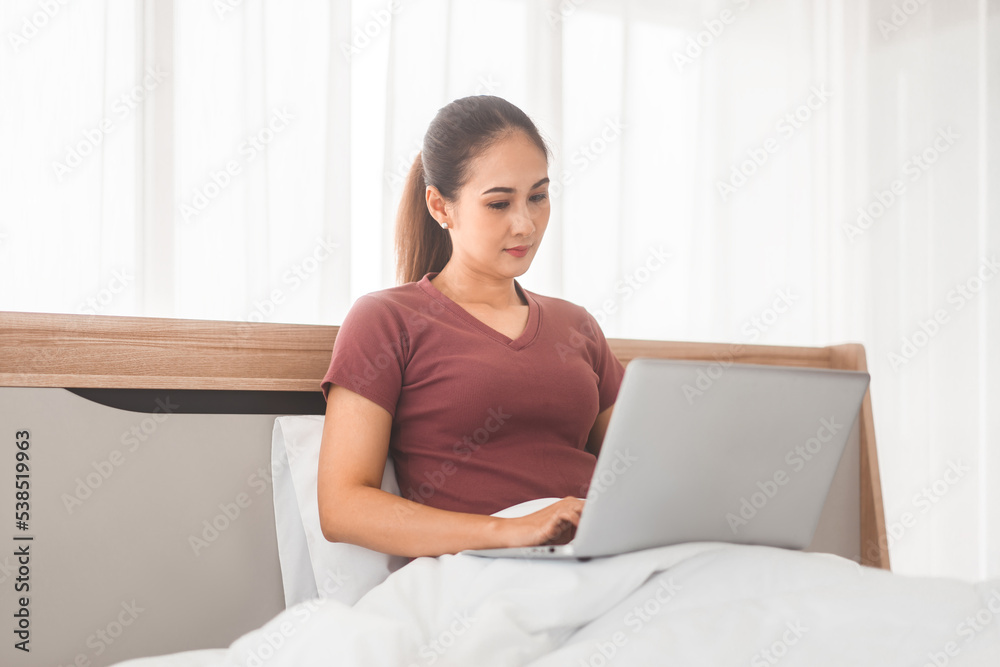 Young adult asian woman using laptop on bed for telemedicine mental health or shopping online Young adult asian woman using laptop on bed for telemedicine mental health or shopping online