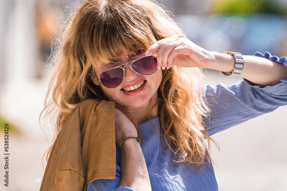 portrait of smiling mature woman in sunglasses and jacket on the street portrait of smiling mature woman in sunglasses and jacket on the street