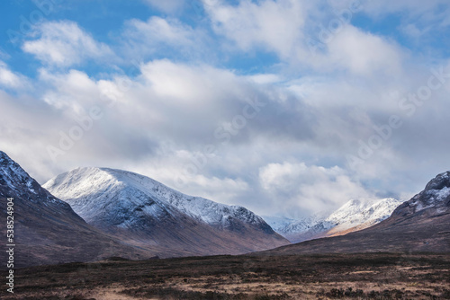 Majestic beautiful Winter landscape image of Lost Valley in Scotland with snowcapped Buachaile Etive Baeg sand distant mountain range with dramatic sky