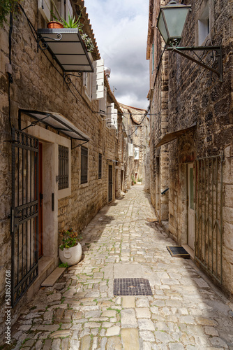 Fototapeta Naklejka Na Ścianę i Meble -  Narrow streets in the old town of Trogir on the Croatian Mediterranean coast. The old houses are built of natural stone.