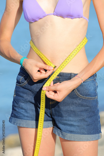 skinny girl measures the waist with tape measure