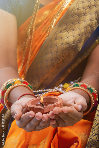 Cute indian maharashtrian little girl holding lamp in hand and celebrate traditional festival Raksha Bandhan or Diwali
