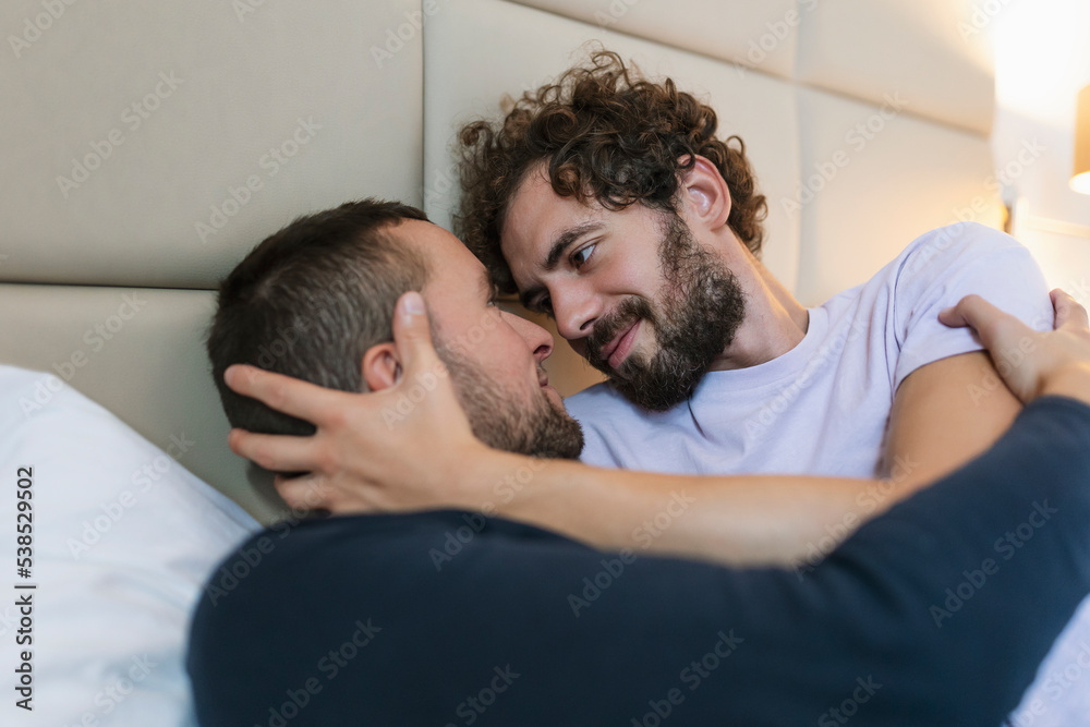 Handsome gay couple lying in bed together. Romantic young gay couple