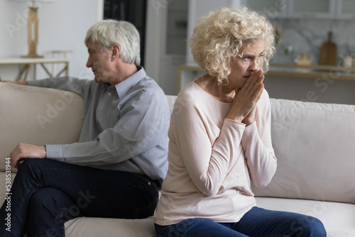 Silent older wife and husband sit apart in couch feel dissatisfied with relations, having problems in marriage, think about break up, divorce. Crisis in relationships, abuse, marriage split, betrayal